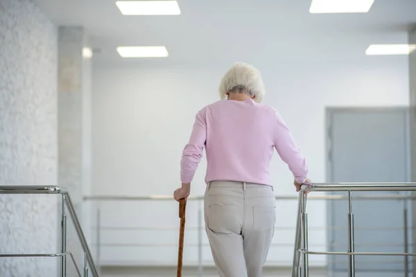 Grauhaarige Frau mit Gehstock geht die Treppe hinauf — Stockfoto