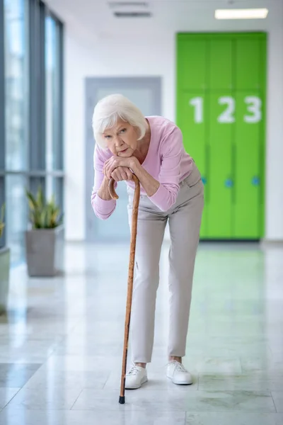 Vecchia donna con un bastone da passeggio in piedi nel corridoio — Foto Stock