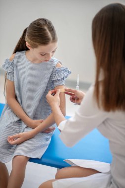 Koyu saçlı doktor kızların kolunu tutuyor ve alçı uyguluyor.