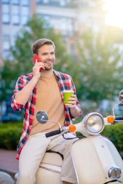 Telefonda konuşan ve kahve içen adam.