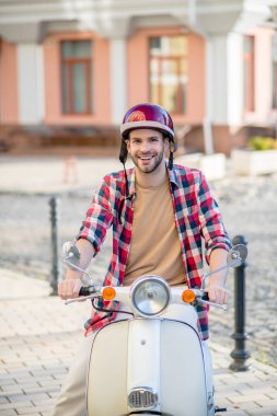 Beyaz scooterına binen kasklı bir adam.