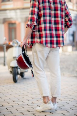 Elinde şık kırmızı bir retro kask tutan adam.