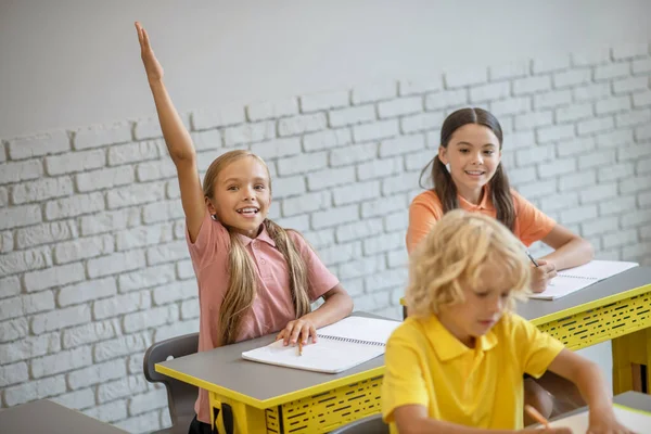 Långhårig flicka räcker upp handen redo att svara — Stockfoto