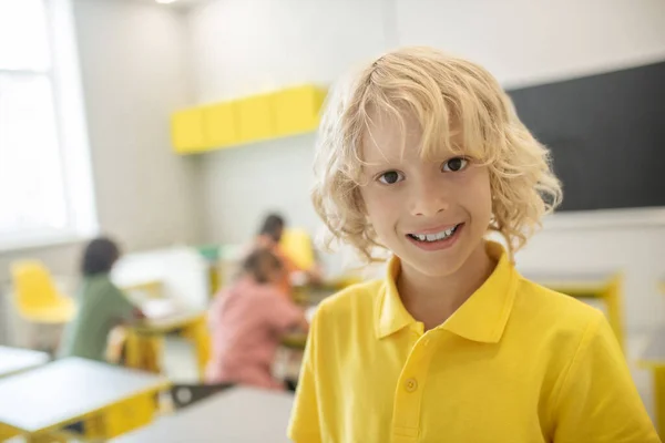 Мила школярка в жовтій сорочці посміхається красиво — стокове фото