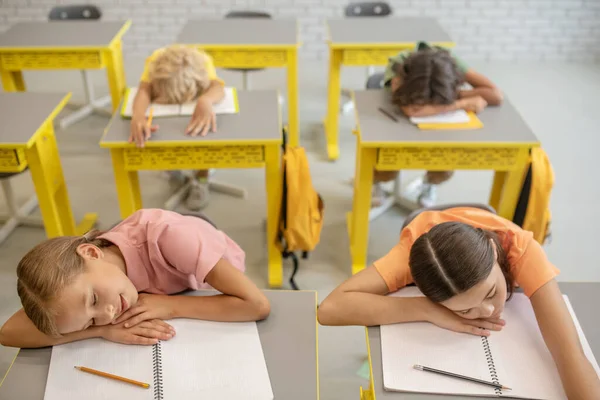 Colegiales cansados durmiendo en los escritorios del aula —  Fotos de Stock