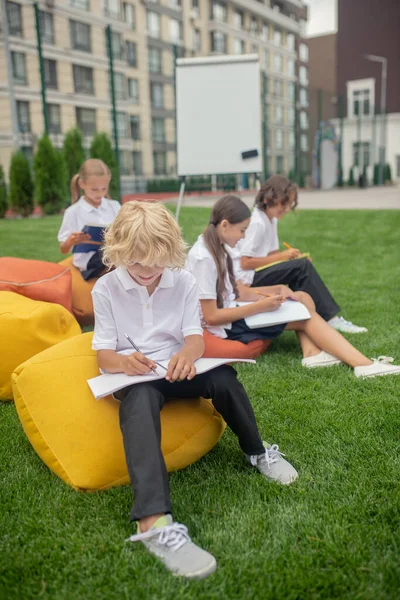 Grupa uczniów biorących lekcje na zewnątrz i wyglądających na skoncentrowanych — Zdjęcie stockowe
