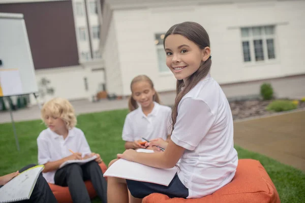 Uma menina de camisa branca sentada na aula e sorrindo — Fotografia de Stock