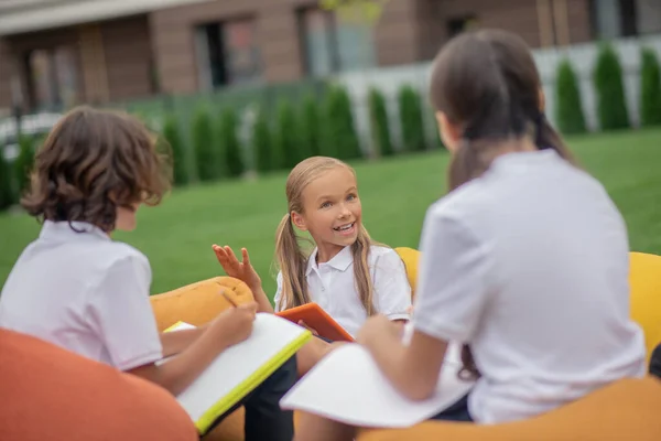 Niños con camisas blancas estudiando juntos y luciendo positivos — Foto de Stock