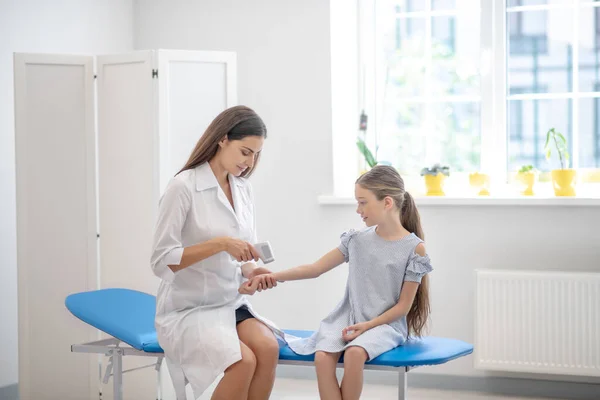 Dottore seduto sul divano e controllare la temperatura dei bambini — Foto Stock