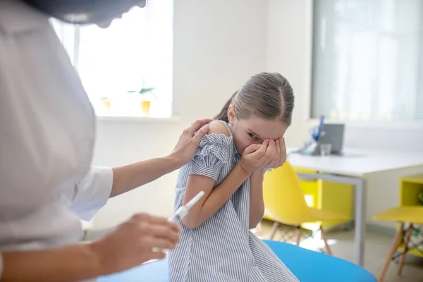 Chica en un vestido azul sentado junto al médico y sintiéndose estresado — Foto de Stock