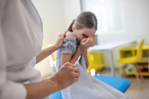 Дівчина дивиться на шприц в руці лікарів і відчуває страх — стокове фото