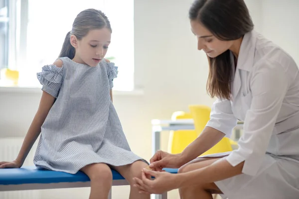 Médico aplicando yeso en la rodilla de las niñas —  Fotos de Stock