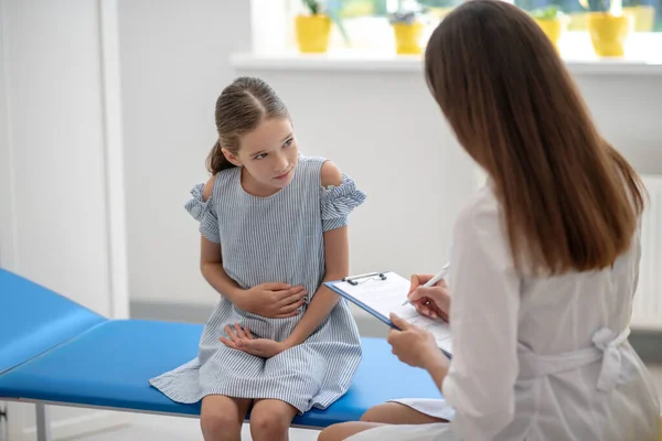 Menina com dor de estômago e conversando com o médico feminino — Fotografia de Stock