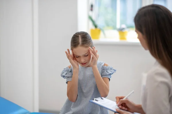 Menina com dor de cabeça e conversando com o médico feminino — Fotografia de Stock