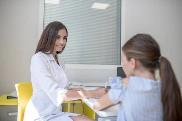 Dziewczyna w niebieskiej sukience ma tutorial w klinice z lekarką — Zdjęcie stockowe