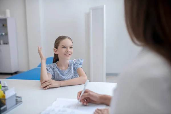 Ragazza avendo un tutorial in clinica con un medico femminile e alzando la mano — Foto Stock