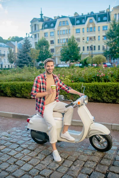 Hombre guapo montando un scooter retro blanco — Foto de Stock