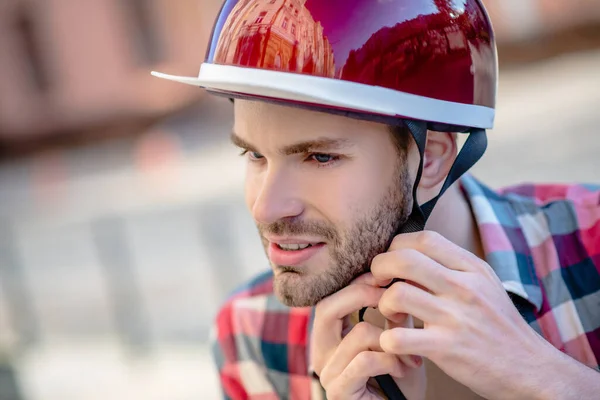 Man putting on a red helmet while riding a scooter — Stock Photo, Image