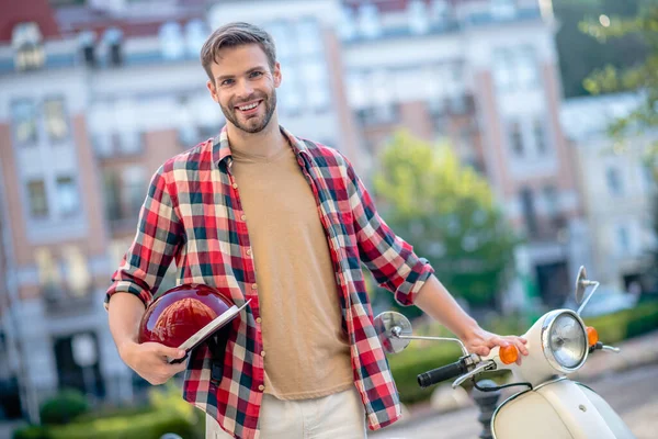 Hombre sonriente sosteniendo un casco retro rojo — Foto de Stock