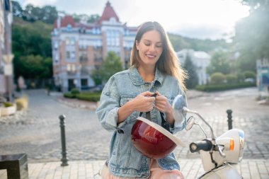 Gülümseyen kadın şık kırmızı bir kask takıyor.