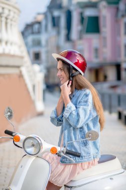 Scooter sürmek için kask takan bir kadın.