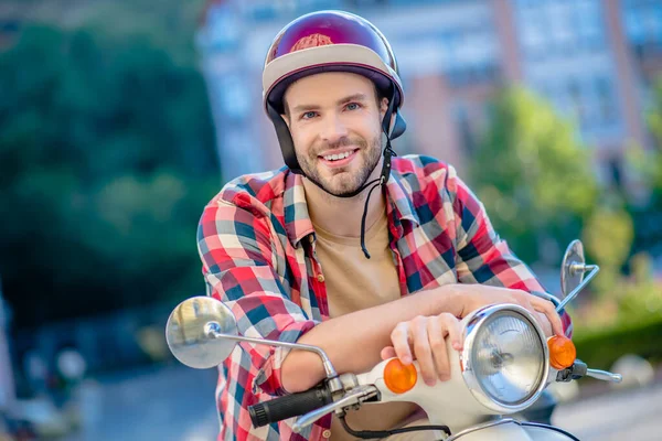 Sorrindo homem bonito sentado em uma scooter — Fotografia de Stock