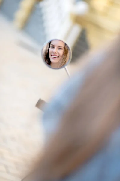 Sorrindo mulher olhando para scooters espelho retrovisor — Fotografia de Stock
