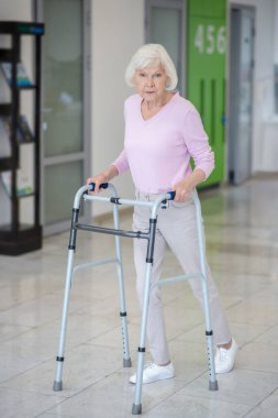 Koridorda yuvarlanan ayaklı yaşlı bir kadın var.