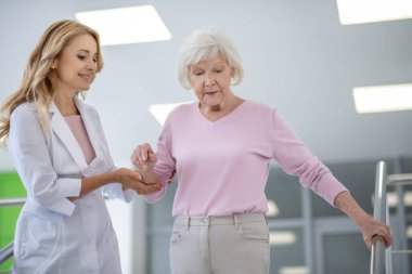 Merdivenlerde hastasını destekleyen önlüklü bir doktor.