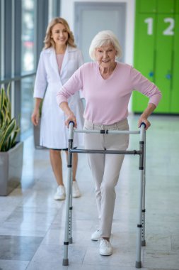 Yürüyen kadın klinikte rehabilitasyon prosedürü uyguluyor.