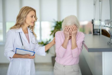 Kıdemli kadın doktorla konuşuyor ve umutsuz görünüyor.