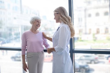 Doktor ve hasta pencerenin yanında durup konuşuyorlar.