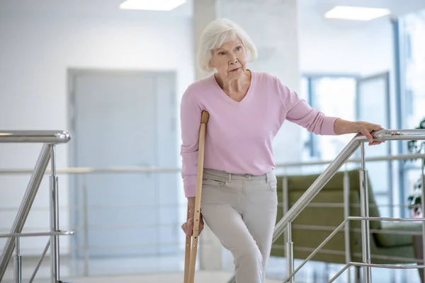 Oudere vrouw met een kruk loopt naar boven — Stockfoto