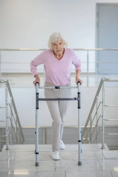 Пожилая женщина с коляской на лестнице — стоковое фото