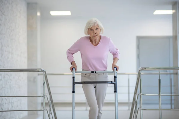 Starší žena s valivým chodítkem vypadá unaveně — Stock fotografie