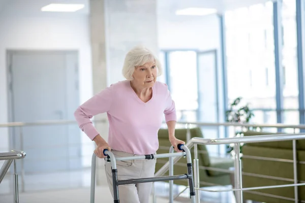 Elderly woman with a rolling-walker looking unhappy — Stock Photo, Image