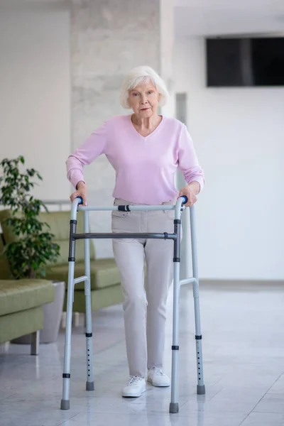 Oudere vrouw met een rollator op zoek vastberaden — Stockfoto