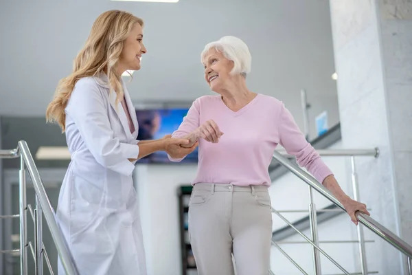 Läkare i en labbrock som stöttar hennes patient och ler — Stockfoto