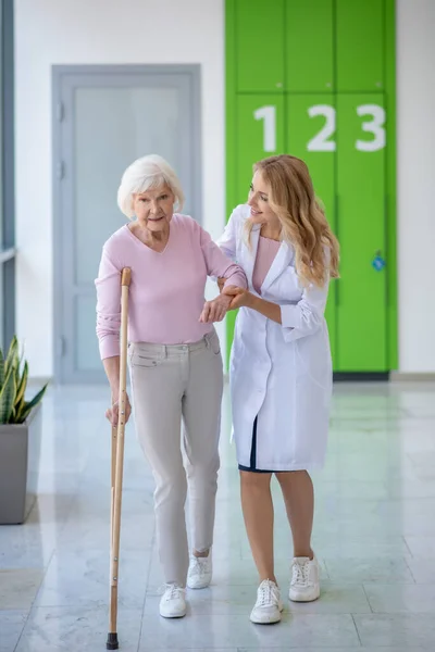 Orvos laborköpenyben és egy beteg együtt sétál a folyosón. — Stock Fotó