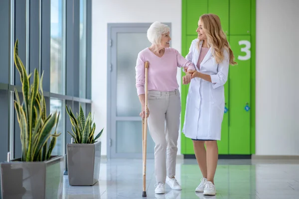 Doctor con una bata de laboratorio y un paciente caminando juntos y hablando —  Fotos de Stock