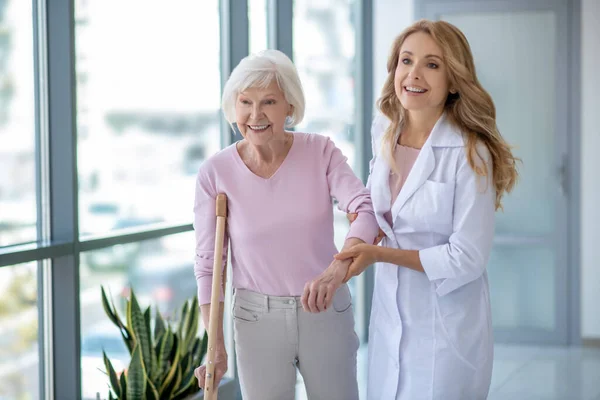 Médico con una bata de laboratorio y un paciente caminando juntos y luciendo positivo — Foto de Stock