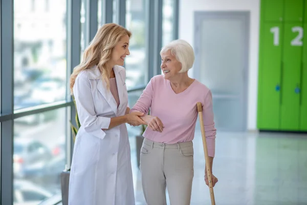Positieve arts in een labjas loopt met een senior patiënt — Stockfoto