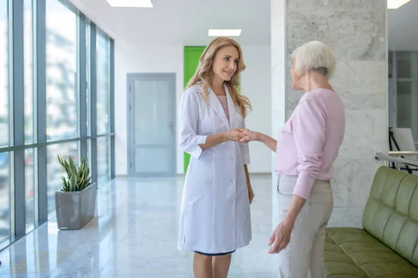 Сіроволоса жінка зустрічає лікаря в клініці — стокове фото