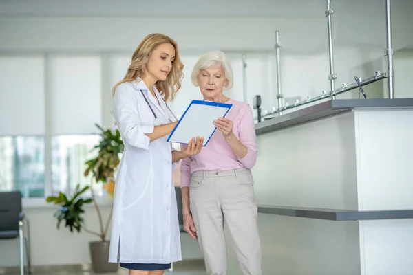 Senior kvinna pratar med läkaren och ser orolig ut — Stockfoto