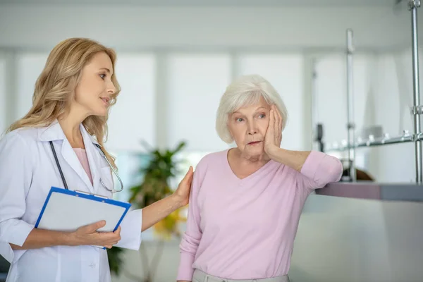 Senior kvinna talar med läkaren och ser frustrerad ut — Stockfoto