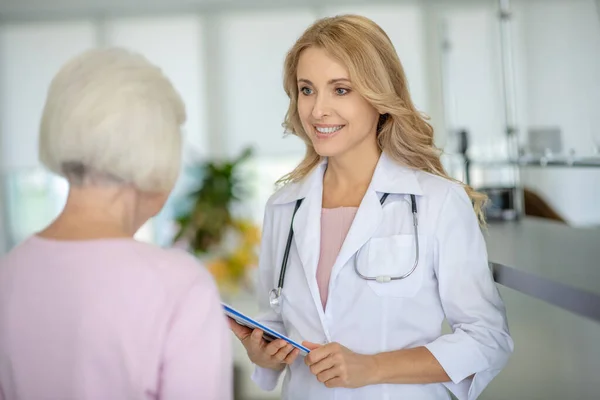 Mujer mayor hablando con el médico en la clínica — Foto de Stock