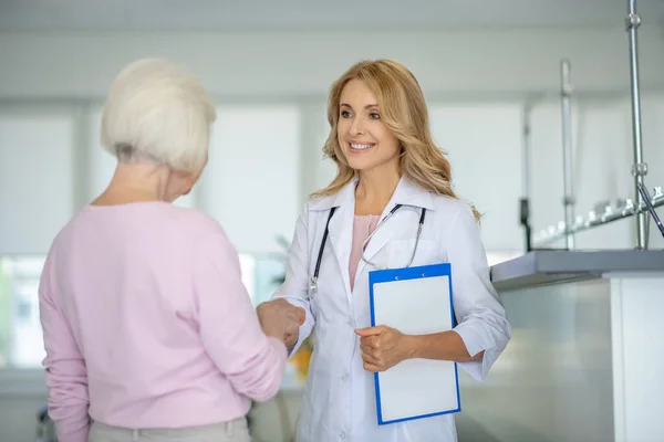 Senior kvinna pratar med läkaren i kliniken korridoren — Stockfoto