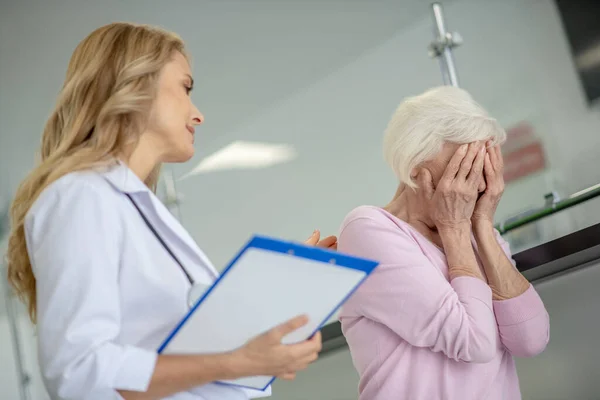 Старшая женщина разговаривает с врачом и чувствует себя отчаявшейся — стоковое фото