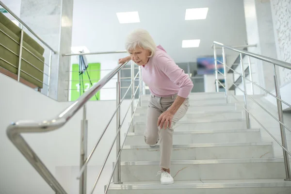 Senior vrouw in roze shirt valt van de trap — Stockfoto
