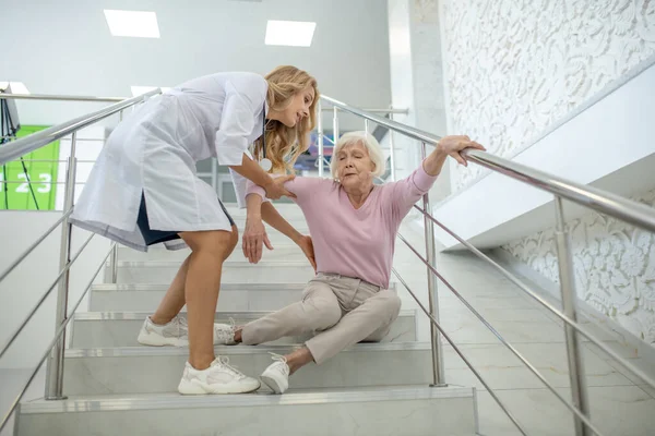 Enfermera rubia ayudando a la mujer mayor que se cayó en las escaleras —  Fotos de Stock